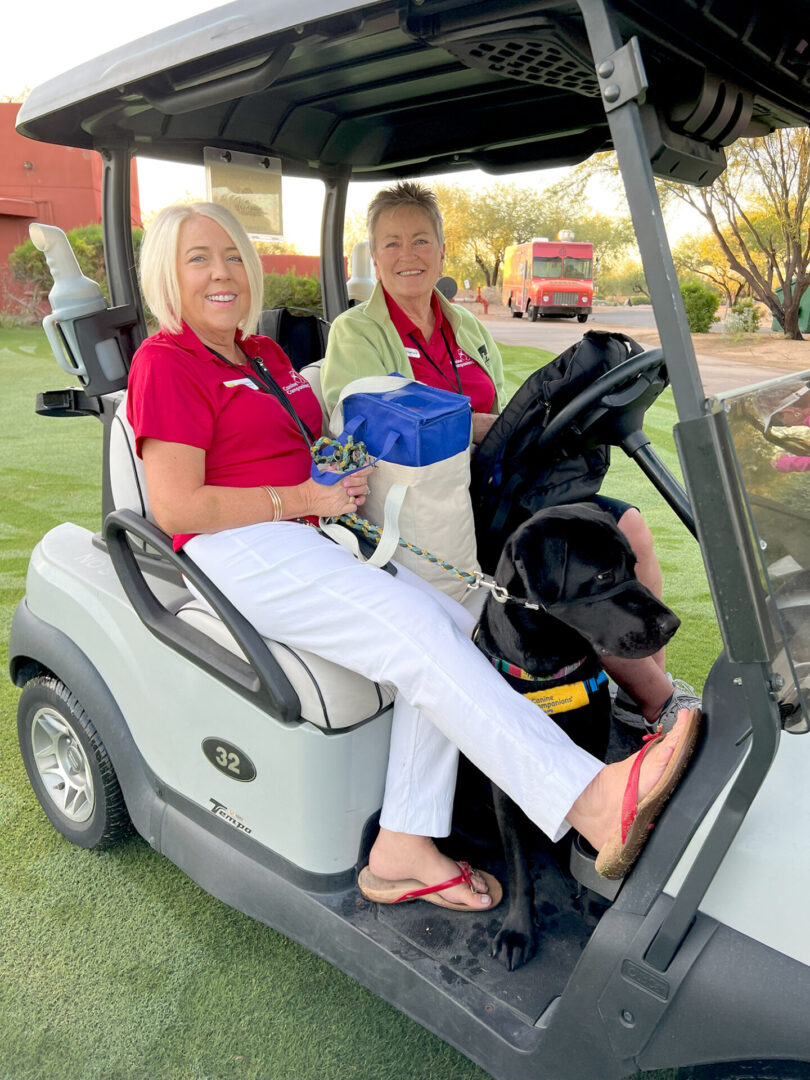 Two smiling women seated in golf cart