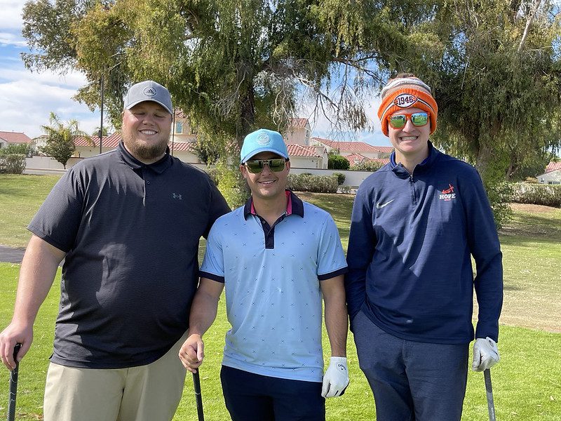 Three smiling golfers on a sunny course