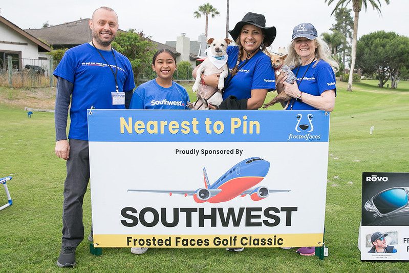 Volunteers with dogs beside Southwest golf sign