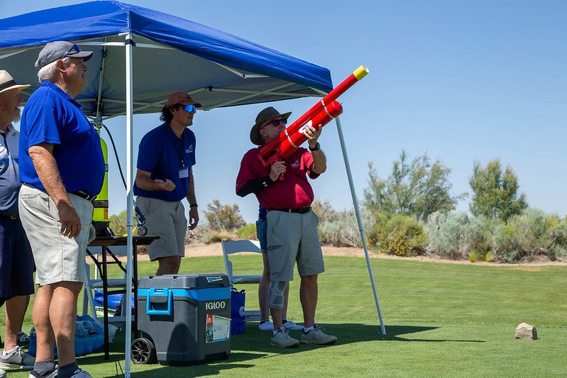 Man aiming red t-shirt cannon on lawn