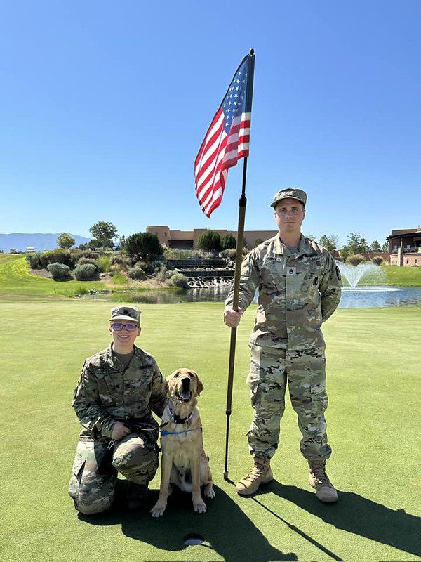 Two soldiers with American flag and service dog