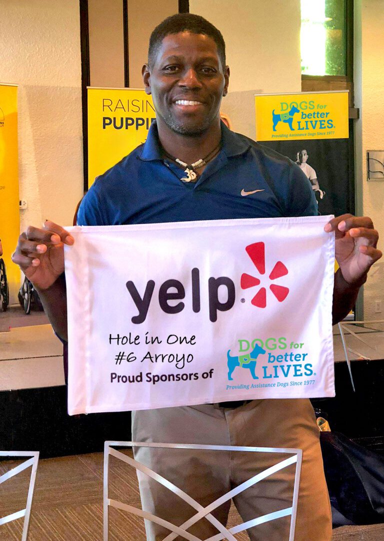 Smiling man holding Yelp banner for dog charity