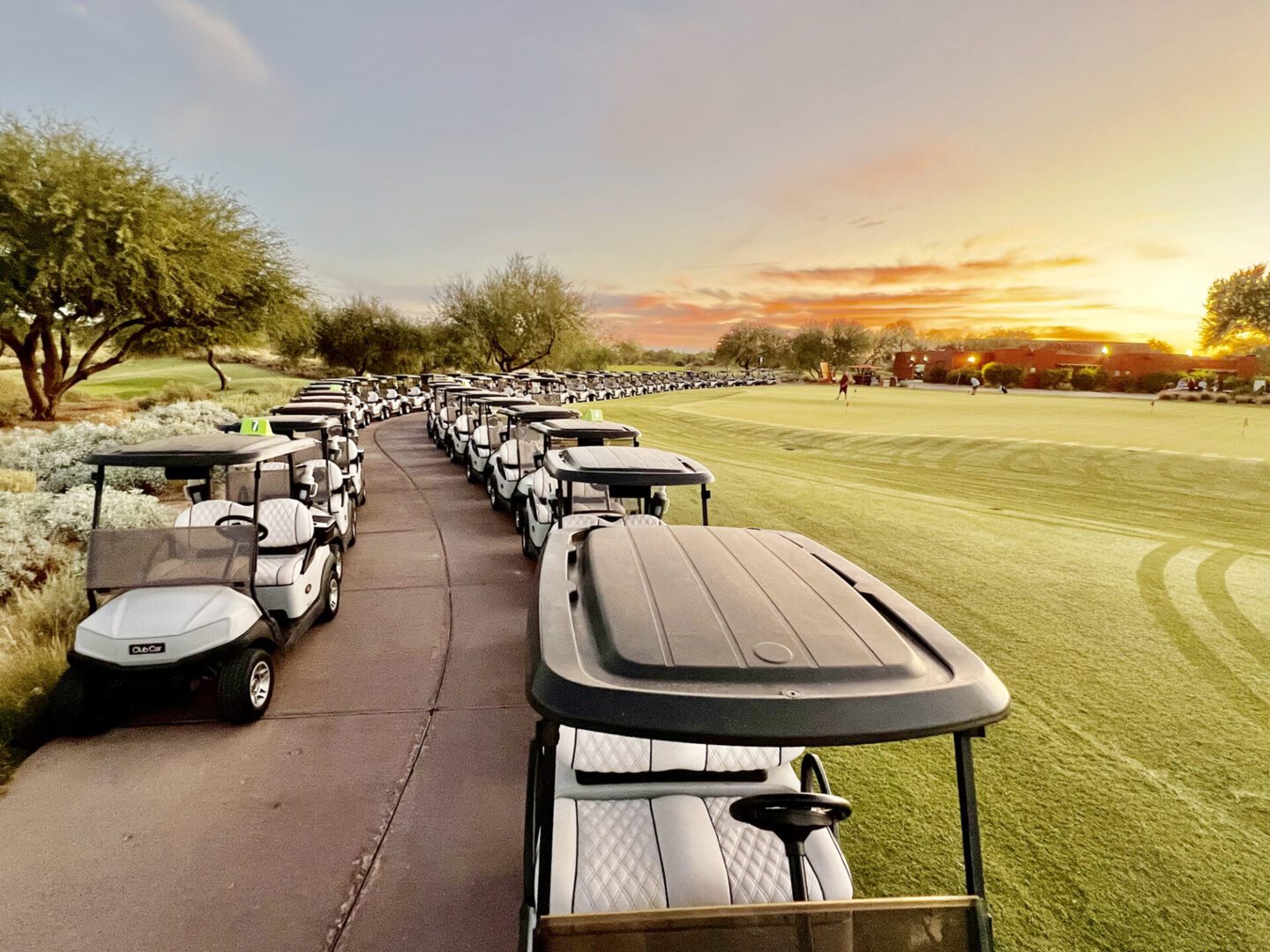 Row of golf carts on path at sunset